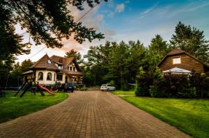 a brick driveway leading to a house with a playground at Domek obok Willi w Rozewiu in Jastrzębia Góra