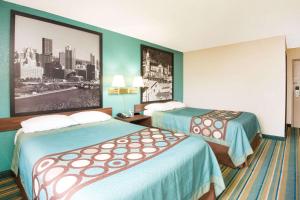 a hotel room with two beds and a picture on the wall at Pittsburgh Royal Hotel in Moon Township
