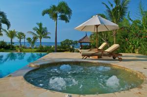 a swimming pool with an umbrella and a chair at Villa Nirwana in Lovina