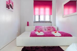 a white bedroom with a pink bed with a purple blanket at Ana's Design Apartments in Lisbon