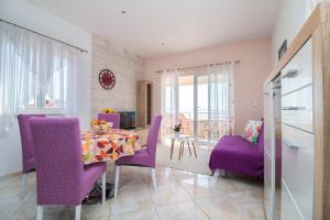comedor con sillas de color púrpura y mesa en Apartments Rakuljic, en Podstrana
