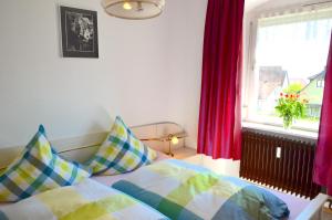 a bedroom with a bed and a window with red curtains at Haus Gnädinger in Hagnau