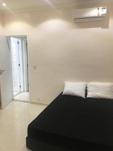 1 dormitorio con cama negra y pared blanca en Luxuoso deslumbrante 100m da praia, en Río de Janeiro
