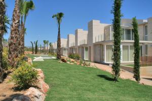 an exterior view of a building with palm trees at L' Escala Resort in L'Escala