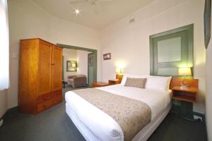 a bedroom with a large white bed and a cabinet at Ballarat Station Apartments in Ballarat