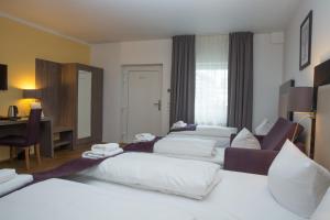 a hotel room with three beds and a desk at Goethe Hotel Messe by Trip Inn in Frankfurt