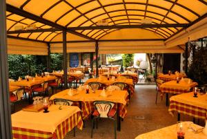 a restaurant with tables and chairs with yellow and orange table cloth at Hotel Fiorentino in Stresa