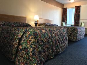 a hotel room with two beds and a table with a lamp at American Inn Kansas City, KS in Kansas City