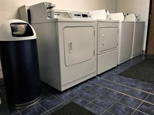 una lavandería con máquinas y un cubo de basura en American Inn Kansas City, KS, en Kansas City