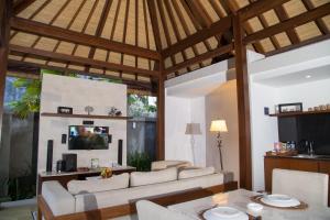 un soggiorno con divani bianchi e TV di The Astari Villa and Residence a Jimbaran