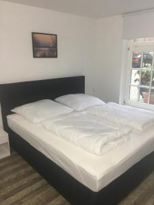 Una cama con sábanas blancas y almohadas en un dormitorio en FEWO Schwerin-Zentrum en Schwerin
