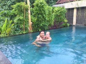 a man and a baby in a swimming pool at Ayu Bungalow 2 in Ubud