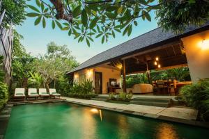 a villa with a swimming pool in front of a house at The Astari Villa and Residence in Jimbaran