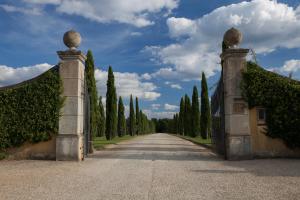 une entrée dans une allée avec des arbres et un bâtiment dans l'établissement Il Borro Relais & Châteaux, à San Giustino Valdarno