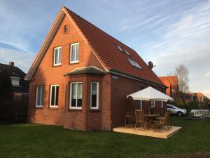 ein rotes Backsteinhaus mit einem Tisch und einem weißen Regenschirm in der Unterkunft Ferienwohnung am alten Fischerspfad in Norden