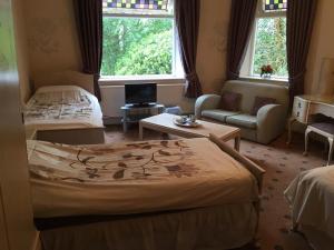 a bedroom with a bed and a couch and a window at Oakfield Lodge Guest House Stockport in Marple