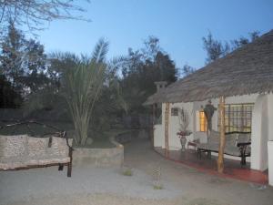 uma pequena casa com um telhado de palha e um pátio em Karen Little Paradise em Nairobi