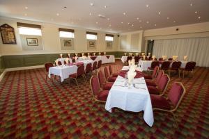 un salón de banquetes con mesas blancas y sillas rojas en The Golf Hotel, en Silloth