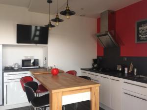 a kitchen with a wooden table and red walls at Maison Landreau in Les Épesses