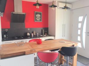 a kitchen with a wooden table and red walls at Maison Landreau in Les Épesses