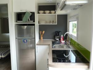 a kitchen with a sink, stove and refrigerator at Eté indien-hôtellerie de plein air in Wimereux