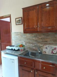 - une cuisine avec des placards en bois et un évier dans l'établissement Alexandra Spingou Apartments, à Dassia