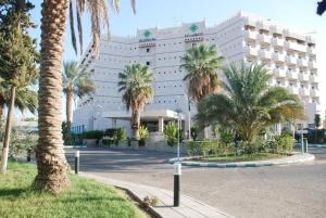 un grand bâtiment avec des palmiers devant lui dans l'établissement Gloria Inn Najran, à Najran