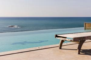 una panchina accanto a una piscina con vista sull'oceano di Beach Villa Pantheon a Pomos