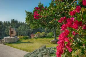 un jardín con flores rosas y una estatua en Evianna Studios en Mousata