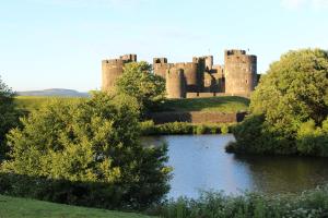 un castillo con un río delante de él en Castell Cottages en Caerphilly