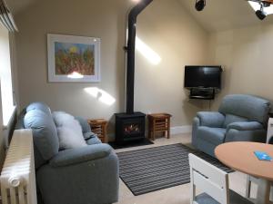 a living room with a couch and a stove at The Old Stables in Hinton Charterhouse