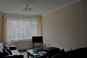 sala de estar con sofá, mesa y ventana en Castell Cottages, en Caerphilly