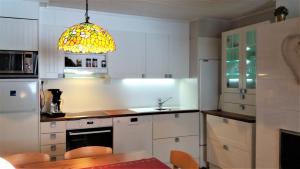 a kitchen with white cabinets and a yellow light fixture at Apartment Saariselkä in Saariselka