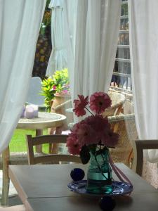 eine Vase mit Blumen auf einem Tisch mit Vorhängen in der Unterkunft Garden House in Velika