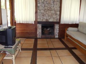 sala de estar con sofá y chimenea en Cabañas El Ocio en Mar de las Pampas