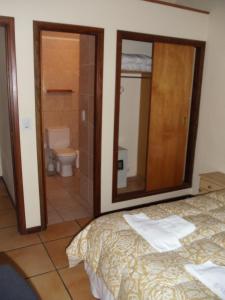 a bedroom with a bed and a bathroom with a toilet at Cabañas El Ocio in Mar de las Pampas