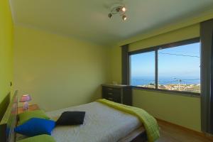 ein Schlafzimmer mit einem Bett und einem großen Fenster in der Unterkunft Casa do Serrado in Ponta do Sol