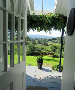una puerta abierta a un porche con vistas a un banco en Plas Tan-Yr-Allt Historic Country House & Estate, en Porthmadog