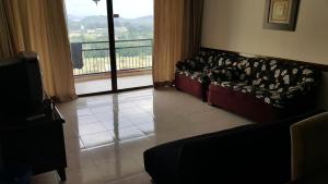uma sala de estar com sofás e uma grande janela em Famosa D Savoy 3-Bedroom Condo in Alor Gajah em Malaca