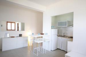 cocina con armarios blancos, mesa y fregadero en Flora en Alcamo Marina