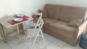 ein Wohnzimmer mit einem Sofa, einem Tisch und einem Stuhl in der Unterkunft Californie Appartement in Nizza