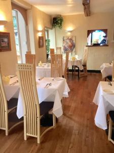un restaurante con mesas y sillas blancas y TV en Villa Bianca B&B en Penrith