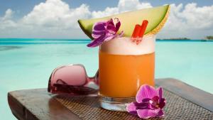 a drink on a table with sunglasses and flowers at Beach Temporada in Aquiraz