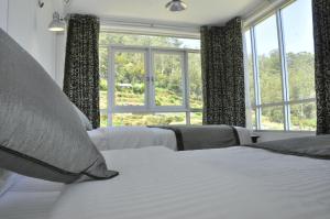 una camera da letto con due letti e una grande finestra di Forest View Lodge a Nuwara Eliya