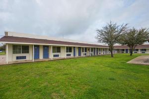 a school building with a green lawn in front of it at Motel 6-Madisonville, TX in Madisonville