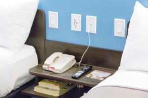 a phone on a table next to a bed at Motel 6-Pottstown, PA in Pottstown