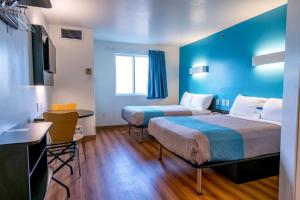 two beds in a room with blue walls and a table at Motel 6-Pottstown, PA in Pottstown +85 photos