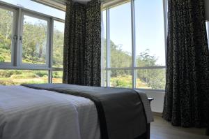 una camera da letto con un letto e una grande finestra di Forest View Lodge a Nuwara Eliya