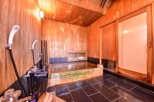 a bathroom with a tub and a sink and wooden walls at Bingoya in Kurashiki
