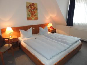 a bedroom with a large white bed with two lamps at Hotel Stadt Munster in Munster im Heidekreis